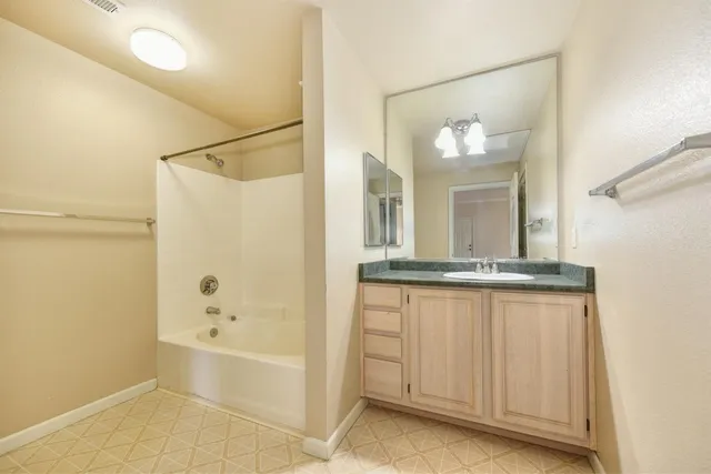 a bathroom with a granite countertop sink a mirror and a bathtub