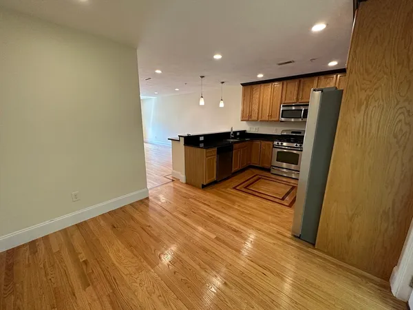 a kitchen with stainless steel appliances granite countertop a refrigerator a sink a stove and island with wooden floor