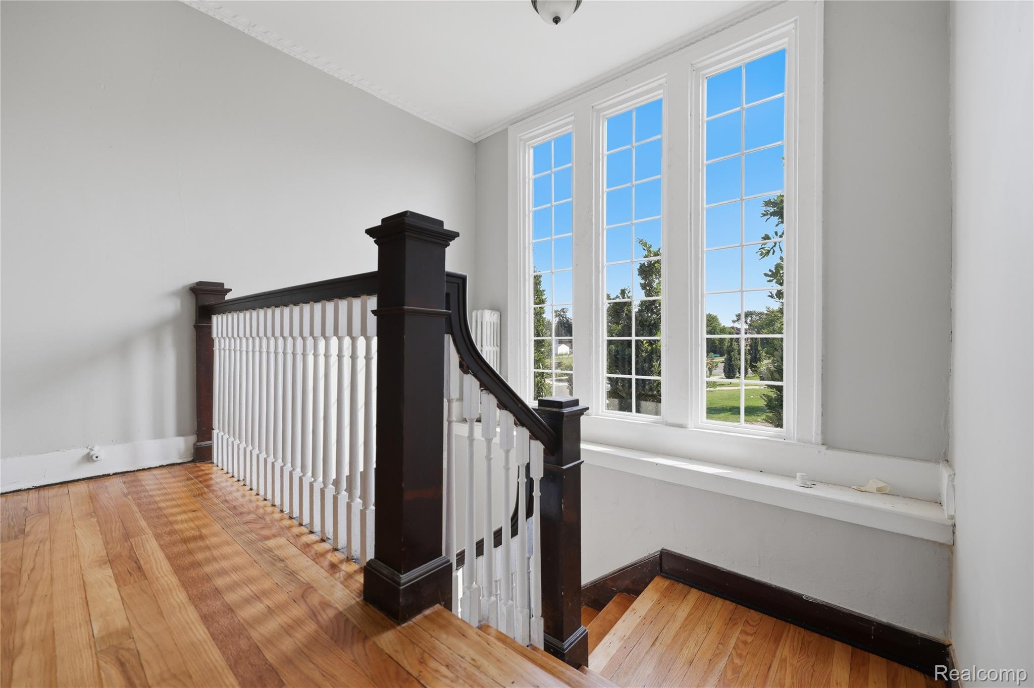 1945 Atkinson Street Detroit, MI 48206 - Photo 23 of 49 Triple sash windows with grid patterns, dark wood-finish newel posts, white balusters, light wood-finish flooring, and white crown molding