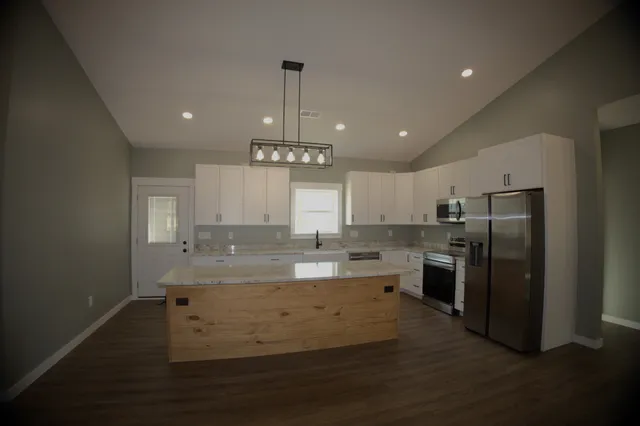 a kitchen with stainless steel appliances granite countertop a stove a sink and a refrigerator