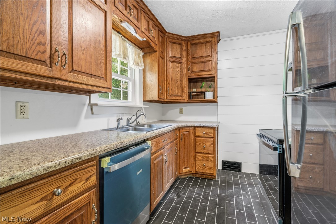 1769 Paradise Road Orrville, OH 44667 - Photo 11 of 36 Kitchen featuring wood cabinetry, light-toned countertops, a double basin sink, black tile flooring in a herringbone pattern, and white horizontal shiplap paneling