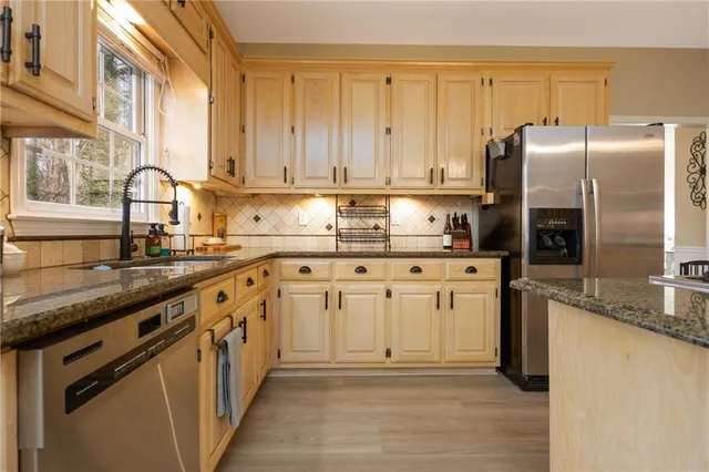 a kitchen with stainless steel appliances granite countertop a refrigerator a stove and white cabinets with wooden floor