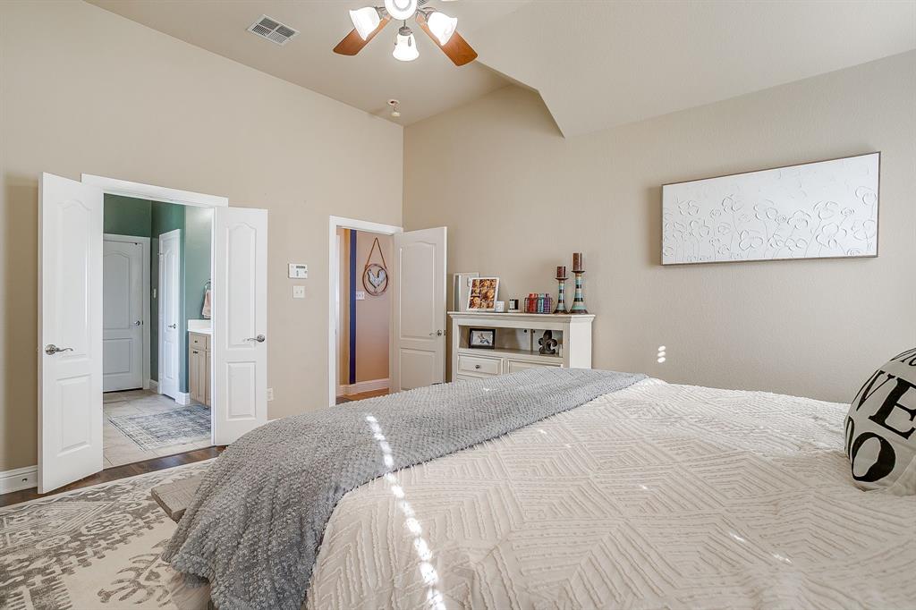 9409 County Road 915 Godley, TX 76044 - Photo 18 of 40 a bedroom with a large bed and a chandelier