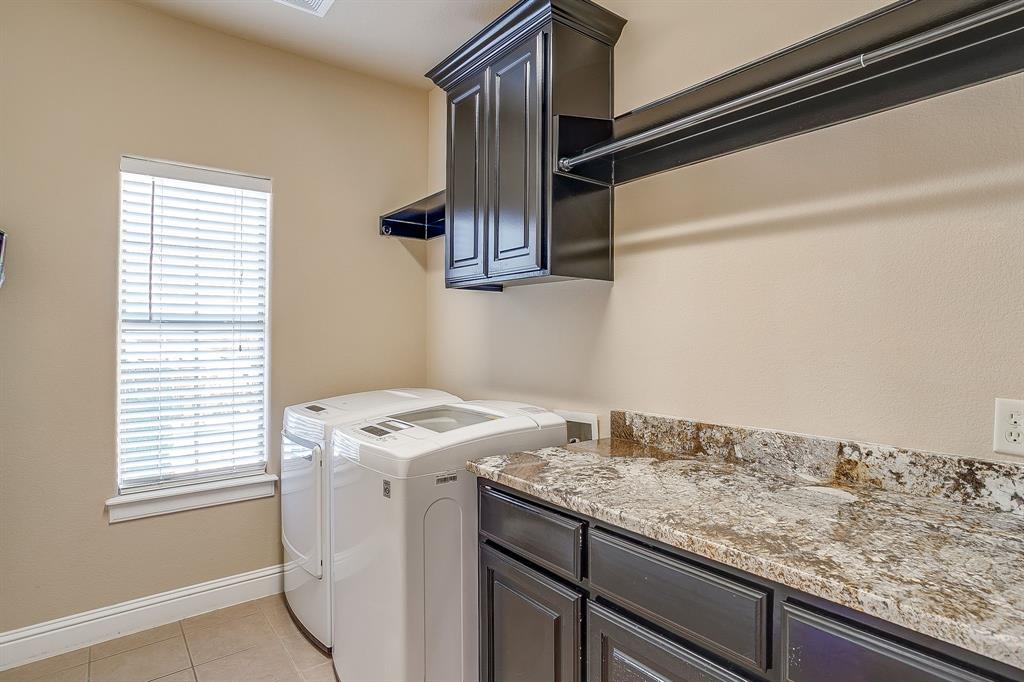 9409 County Road 915 Godley, TX 76044 - Photo 28 of 40 a utility room with granite countertop cabinets washer and dryer