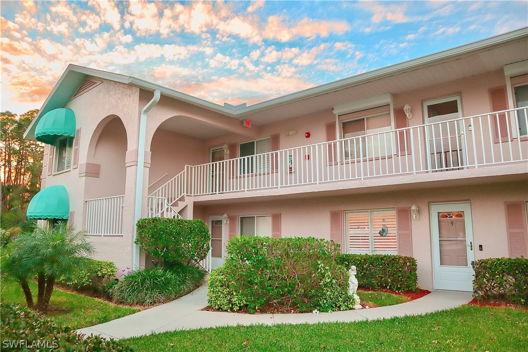121 Gabriel Circle, Unit 10 Naples, FL 34104 - Photo 23 of 25 a front view of a house with garden and trees