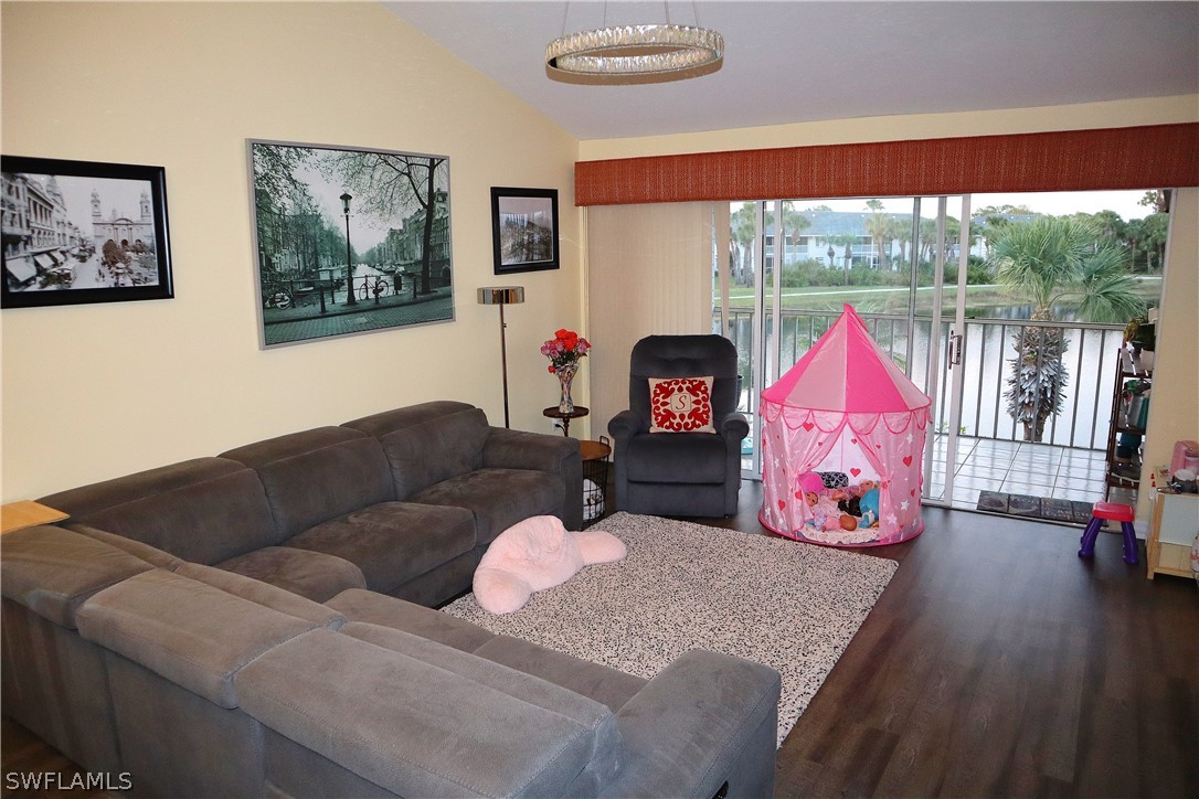 121 Gabriel Circle, Unit 10 Naples, FL 34104 - Photo 8 of 25 a living room with furniture a flat screen tv and a floor to ceiling window