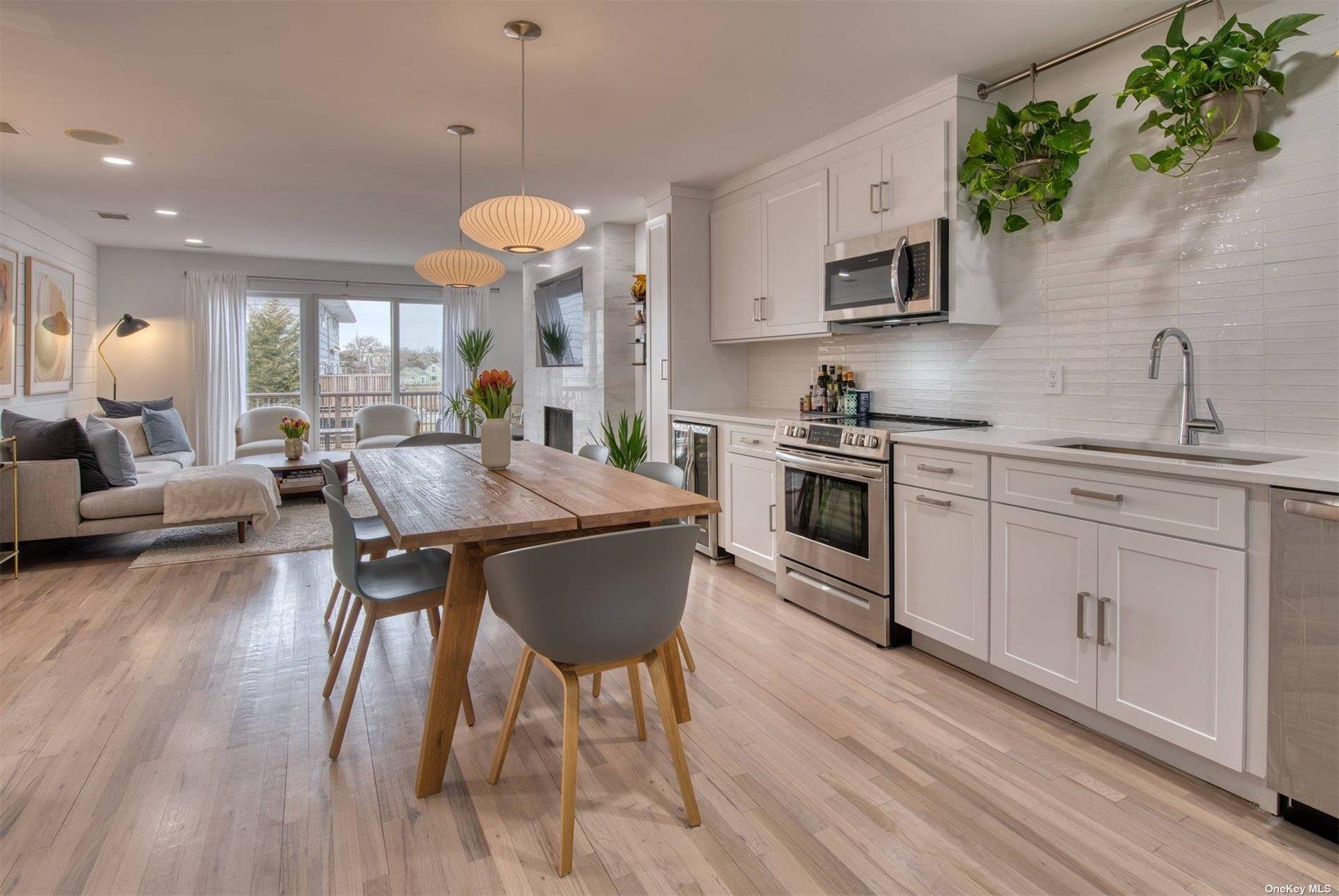 3029 Mitchell Road Westhampton Beach, NY 11978 - Photo 12 of 12 a kitchen with stainless steel appliances a table chairs sink and cabinets