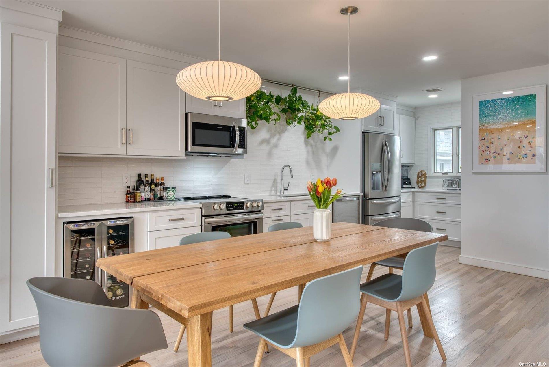 3029 Mitchell Road Westhampton Beach, NY 11978 - Photo 2 of 12 a kitchen with stainless steel appliances granite countertop a stove a sink a microwave a dining table and chairs