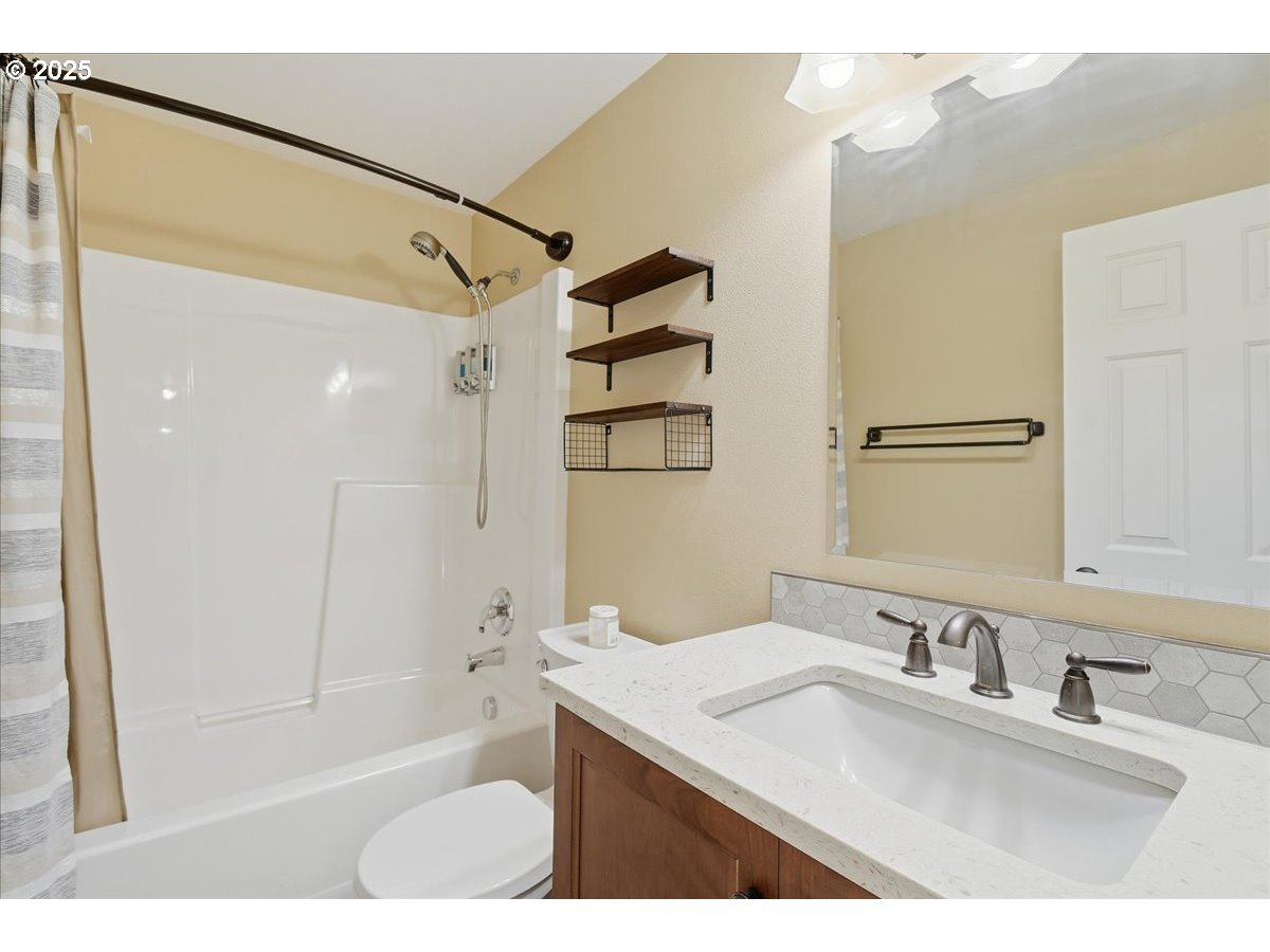 2519 Northwest 13th Street Battle Ground, WA 98604 - Photo 29 of 43 a bathroom with a granite countertop sink a mirror a shower and a bathtub