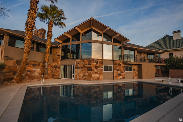 980 Cactus Circle St. George, UT 84790 - Photo 39 of 77 Rear view of house featuring stone siding, a balcony, and an outdoor pool