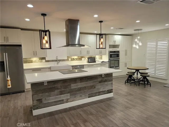 a kitchen with stainless steel appliances a stove a sink cabinets and wooden floor