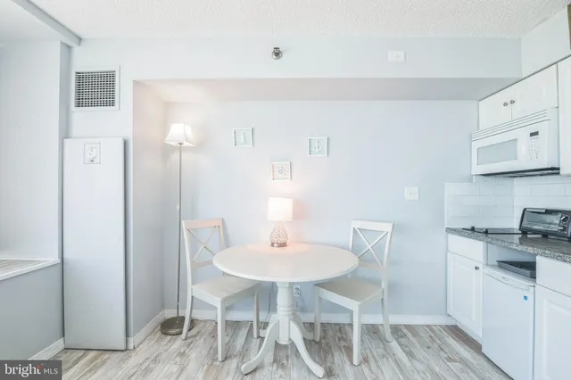 a kitchen with stainless steel appliances a dining table chairs and a refrigerator