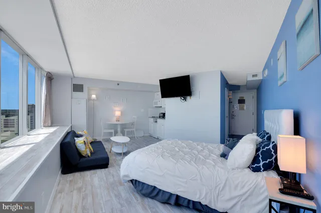 a bedroom with a bed a couch and a flat screen tv