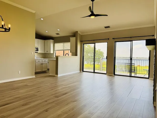 a view of empty room with wooden floor and fan