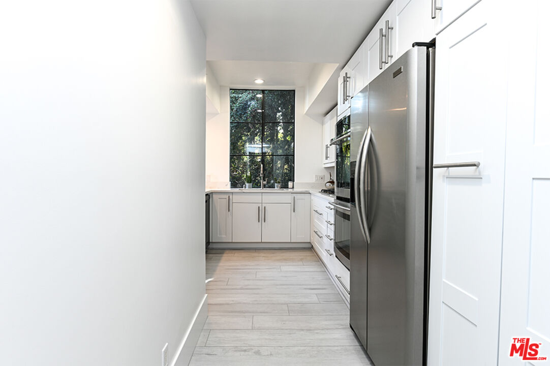 235 South Reeves Drive, Unit 301 Beverly Hills, CA 90212 - Photo 7 of 18 a kitchen with a refrigerator and a sink