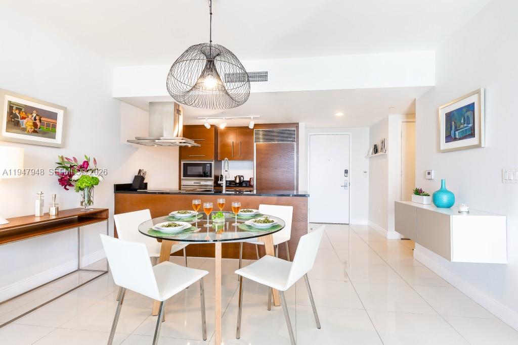 485 Brickell Avenue, Unit 4307 Miami, FL 33131 - Photo 10 of 21 a dining room with wooden floor a chandelier a wooden table and chairs