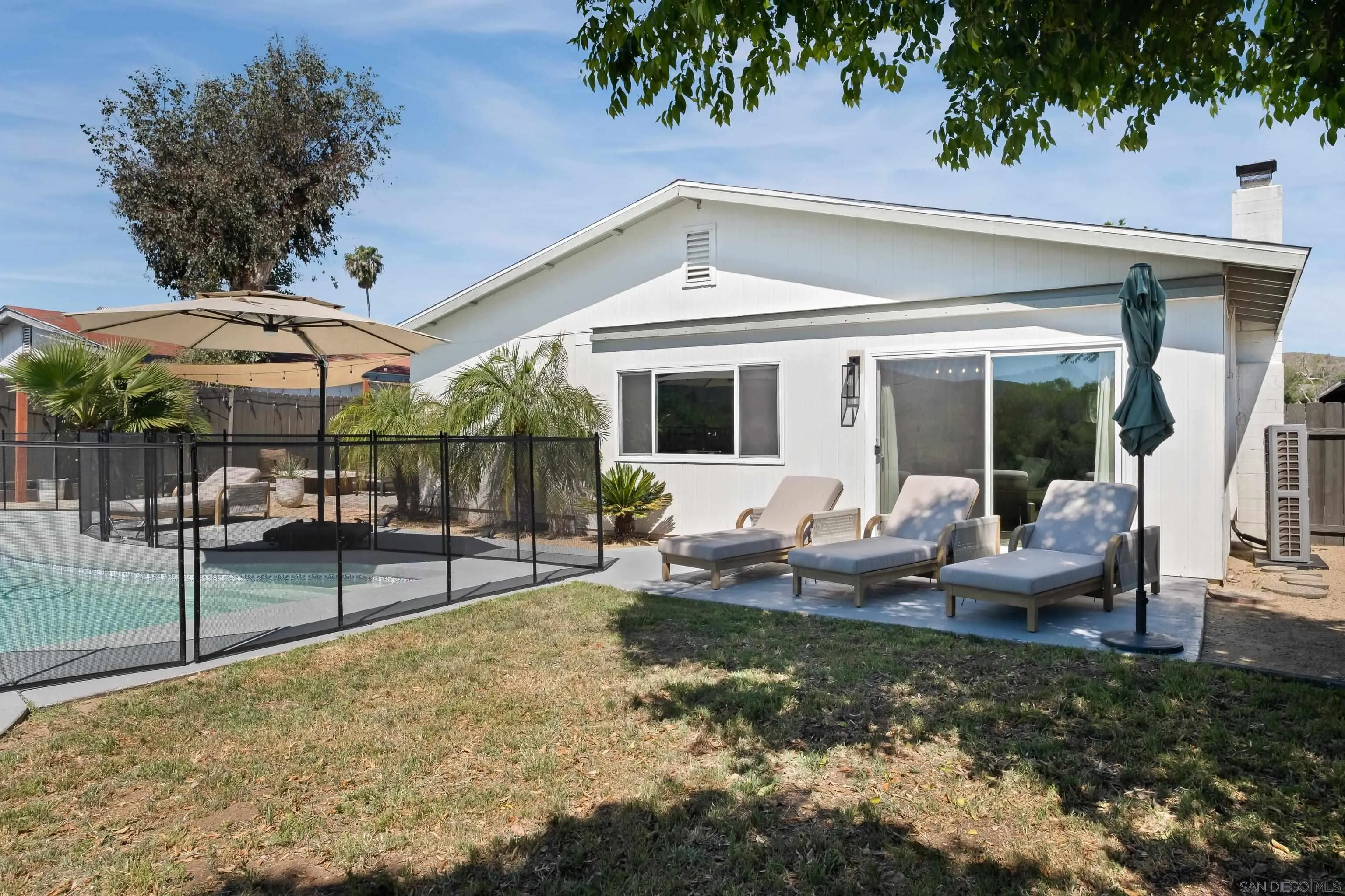 9081 Inverness Road Santee, CA 92071 - Photo 40 of 53 a view of a patio with couches table and chairs under an umbrella with a small yard