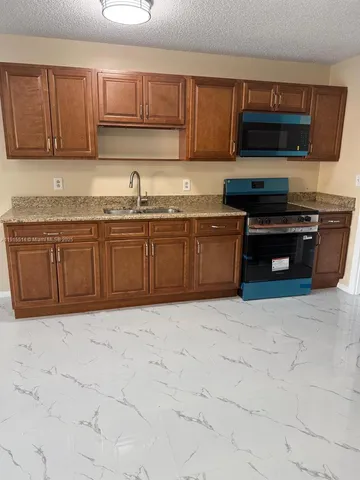 a kitchen with granite countertop a sink a stove and cabinets