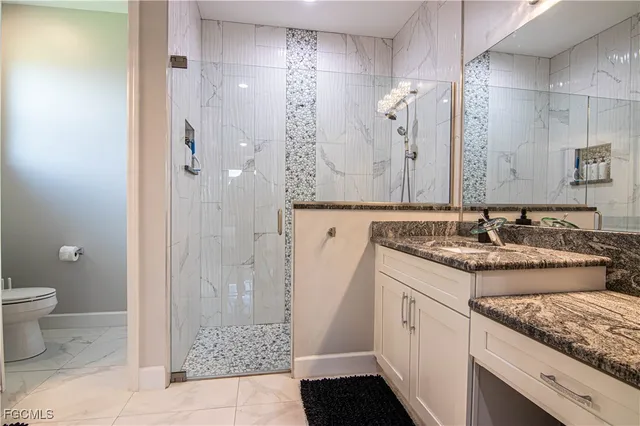 a bathroom with a granite countertop sink a toilet and shower