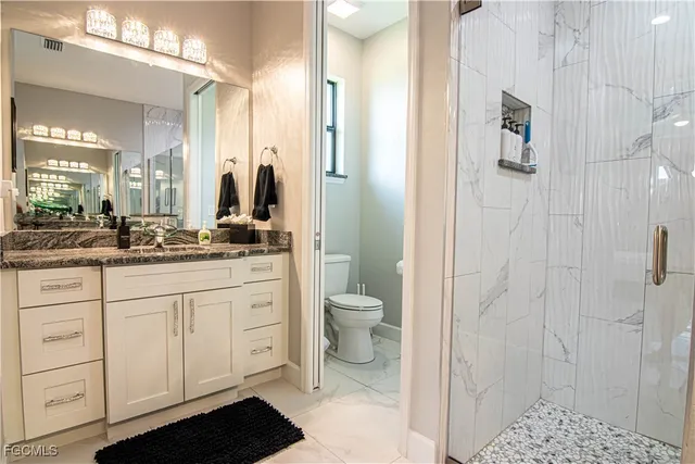 a bathroom with a granite countertop sink toilet and shower