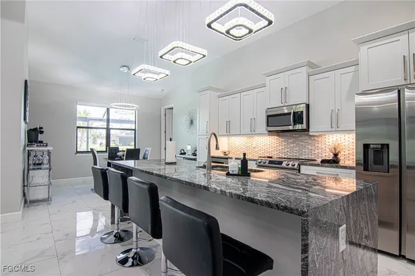 a kitchen with stainless steel appliances granite countertop a sink stove refrigerator and cabinets