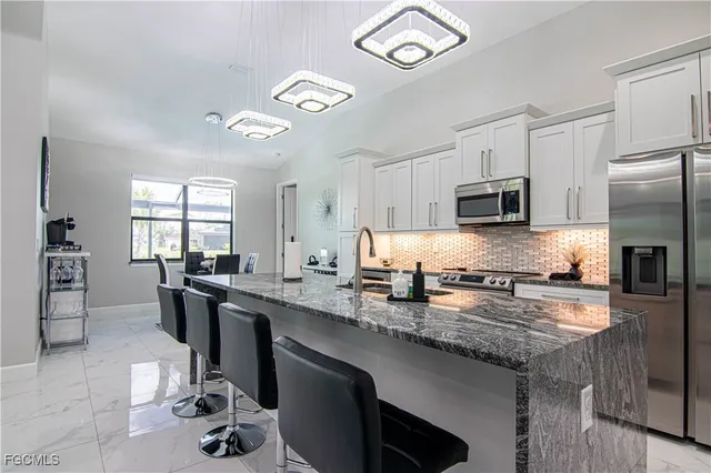 a kitchen with stainless steel appliances granite countertop a sink stove refrigerator and cabinets