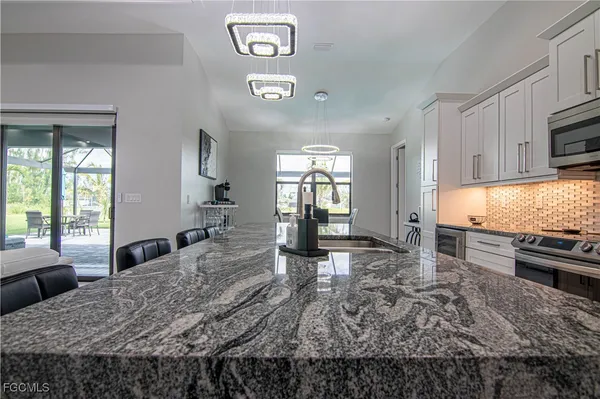 a large kitchen with kitchen island granite countertop a stove a sink a dining table and chairs with wooden floor