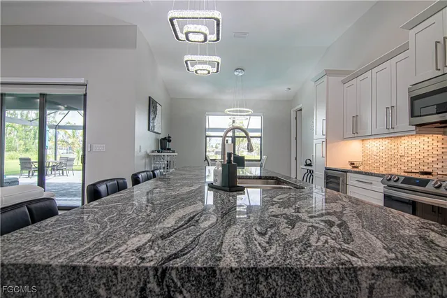 a large kitchen with kitchen island granite countertop a stove a sink a dining table and chairs with wooden floor