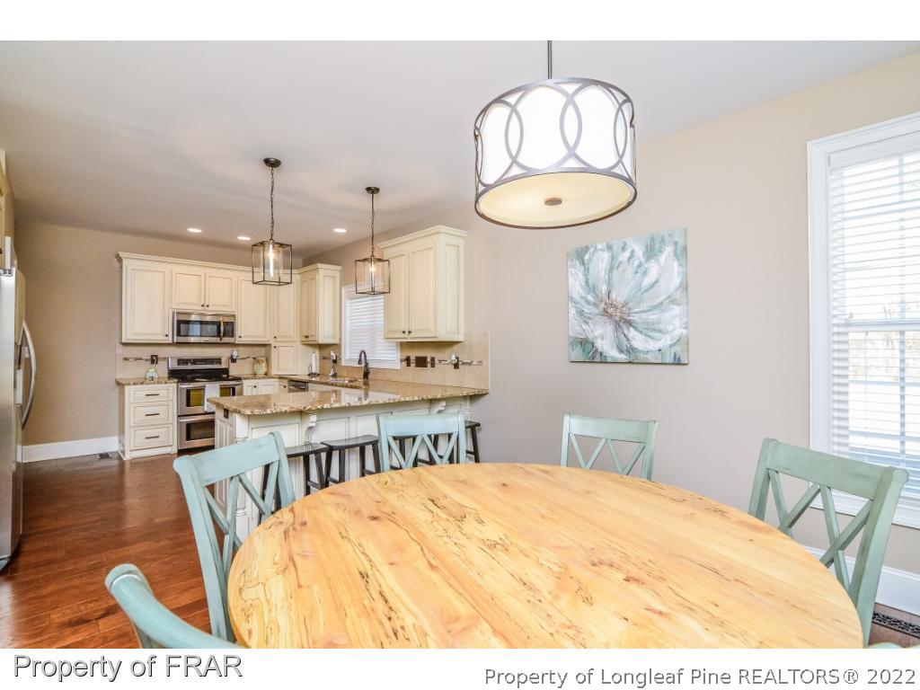 5491 Murphy Road Stedman, NC 28391 - Photo 11 of 33 a kitchen with stainless steel appliances kitchen island granite countertop a stove a sink a dining table and chairs with wooden floor