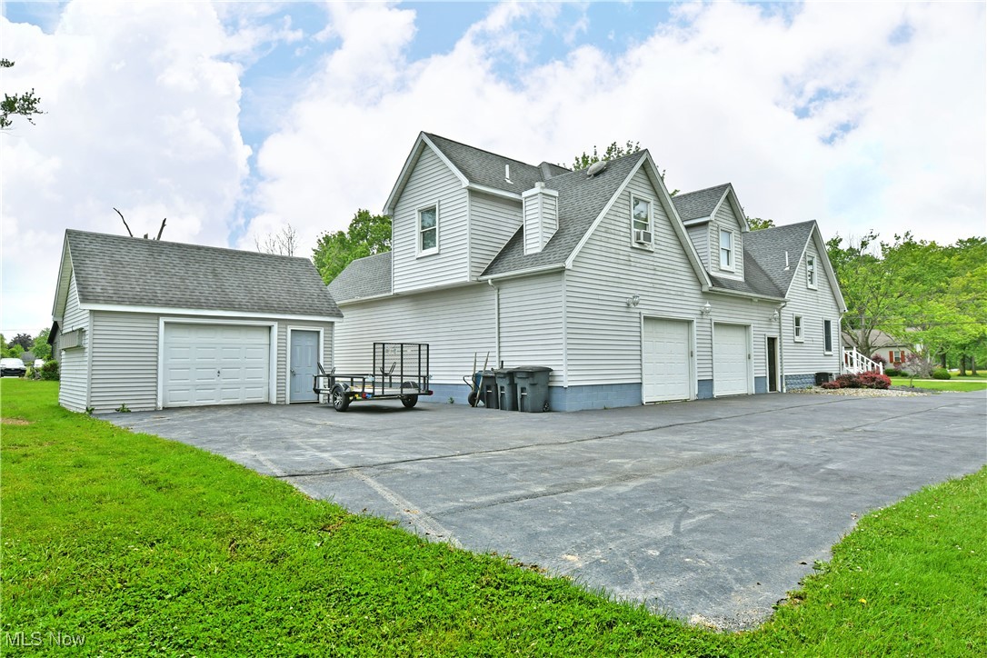 View of side of home featuring roof with shingles, an outbuilding, and a yard