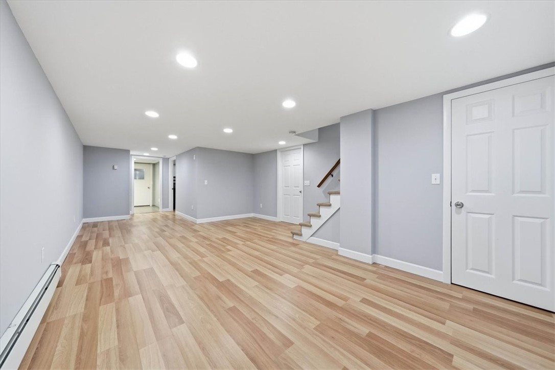 214 Anan Wade Road Glocester, RI 02857 - Photo 26 of 50 The room feels bright and polished with attractive wood-look laminate flooring, recessed lighting, neutral finishes, and a long, open layout that allows for multiple furniture arrangements and activity zones.