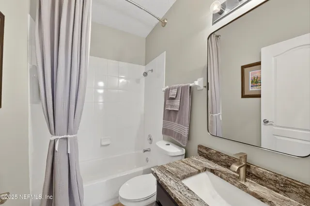 a bathroom with a granite countertop sink toilet and mirror
