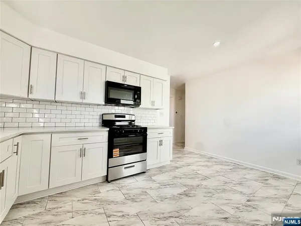a kitchen with granite countertop a stove a sink and a microwave
