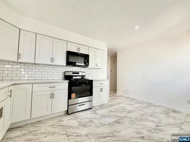 a kitchen with granite countertop a stove a sink and a microwave