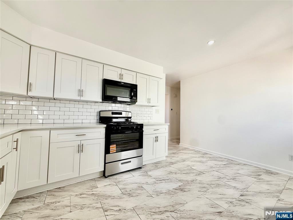 41 Corabelle Avenue, Unit 2 Lodi, NJ 07644 - Photo 11 of 21 a kitchen with granite countertop a stove a sink and a microwave