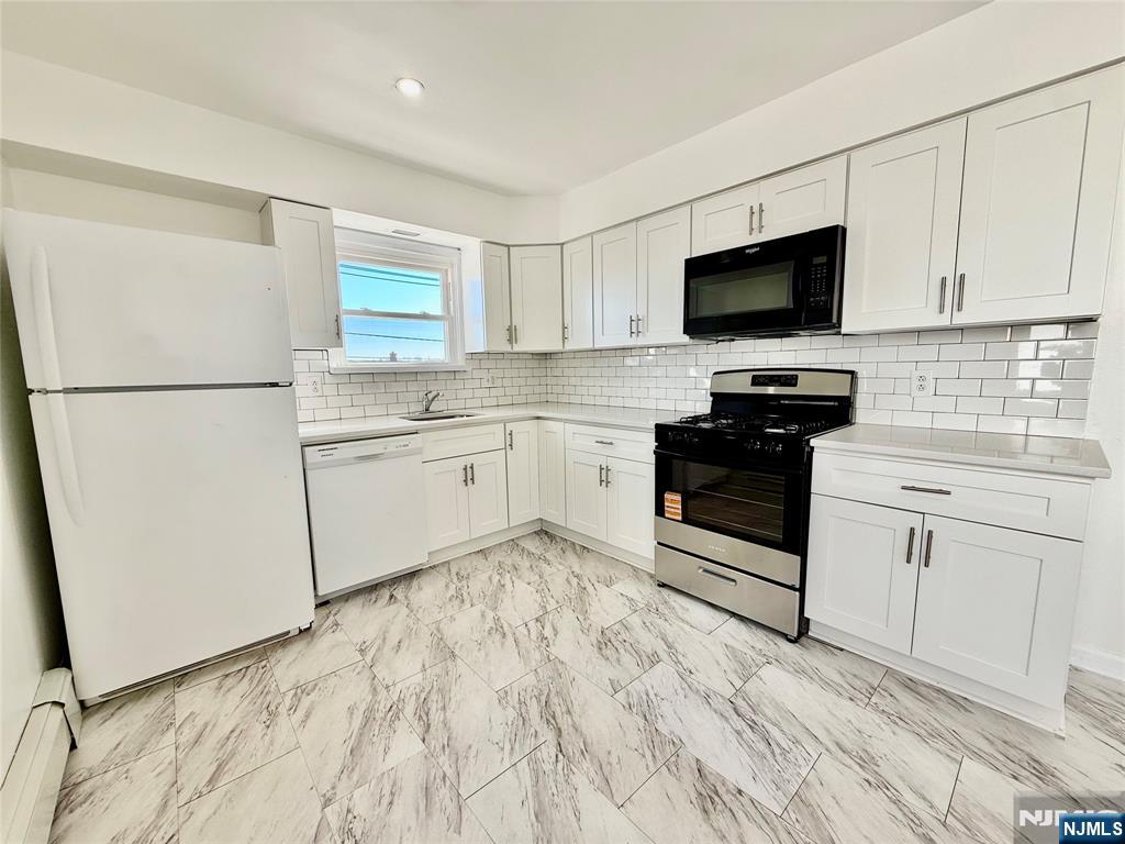 41 Corabelle Avenue, Unit 2 Lodi, NJ 07644 - Photo 10 of 21 a kitchen with white cabinets and appliances