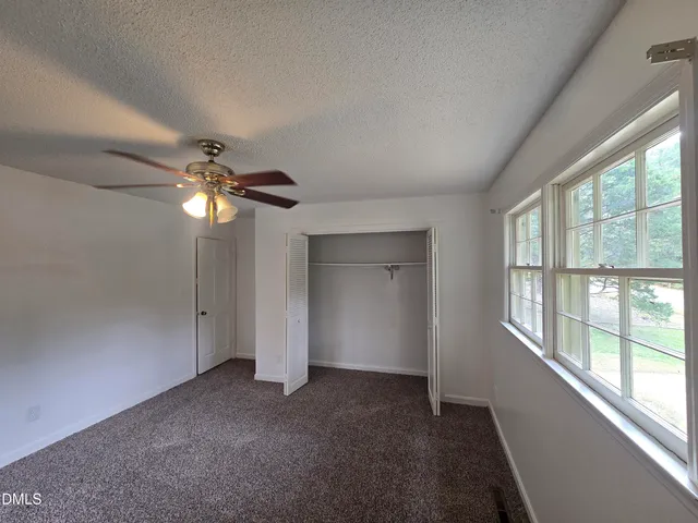 en empty room with windows and ceiling fan