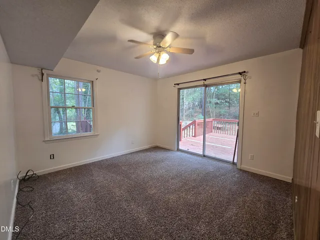 an empty room with windows and ceiling fan