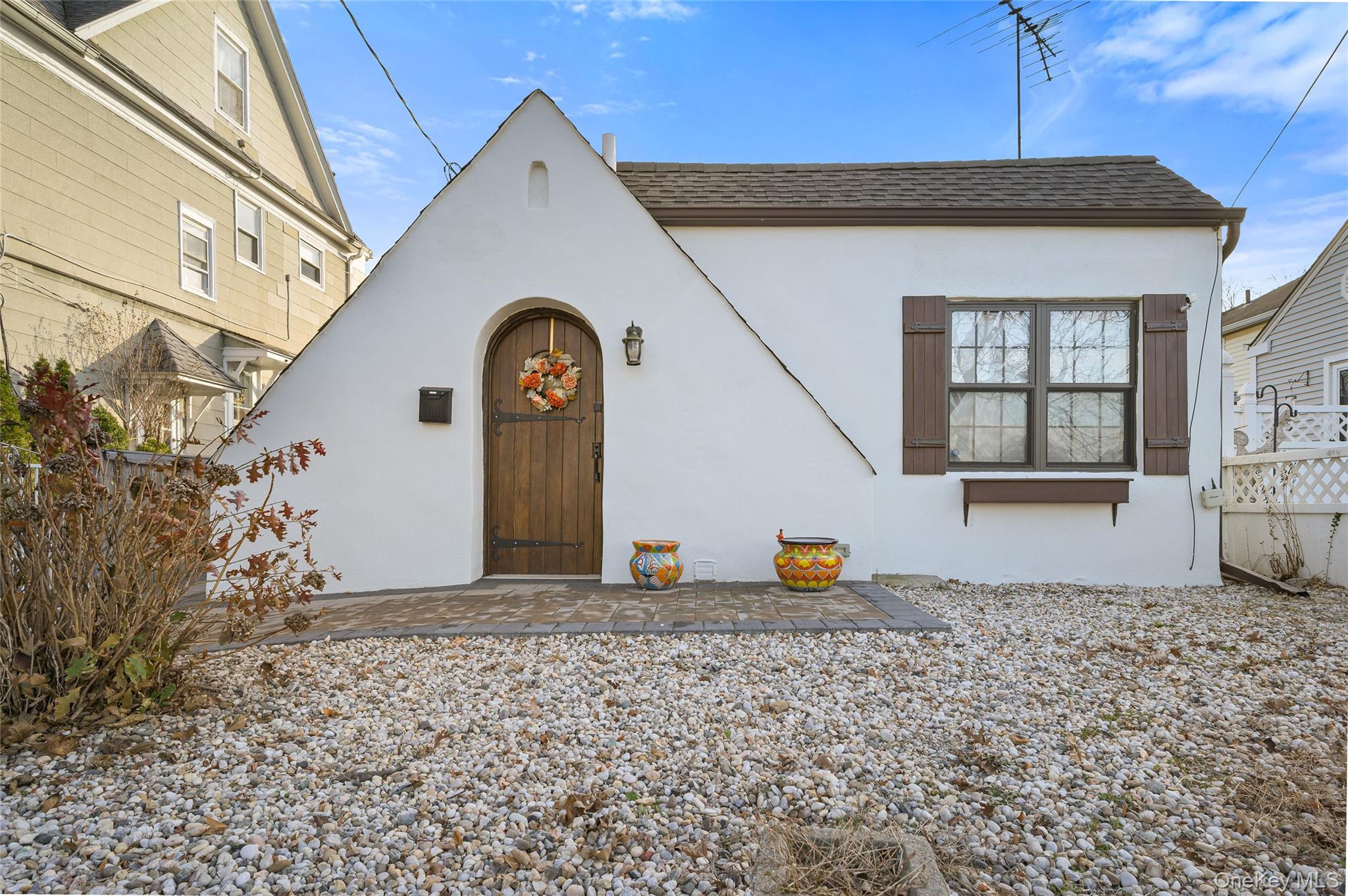 View of front of property with a shingled roof, stucco siding, and a patio