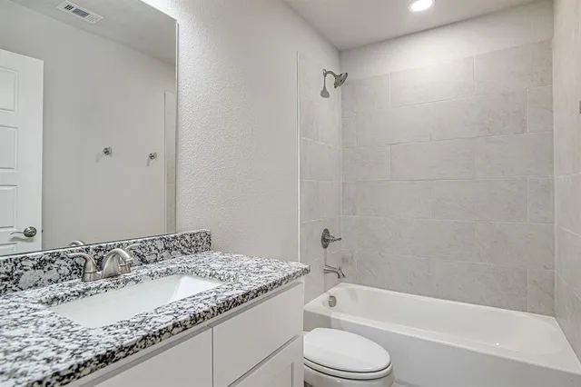 a bathroom with a granite countertop sink toilet and bathtub