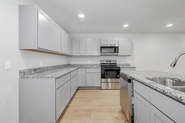 a kitchen with granite countertop a sink stove and cabinets