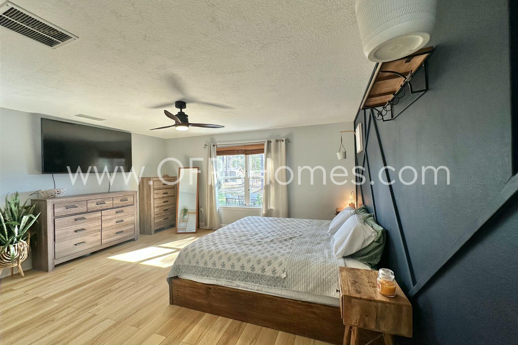 2400 Avenida De Sol Navarre, FL 32566 - Photo 15 of 42 a bedroom with a large bed and a flat tv screen on dresser