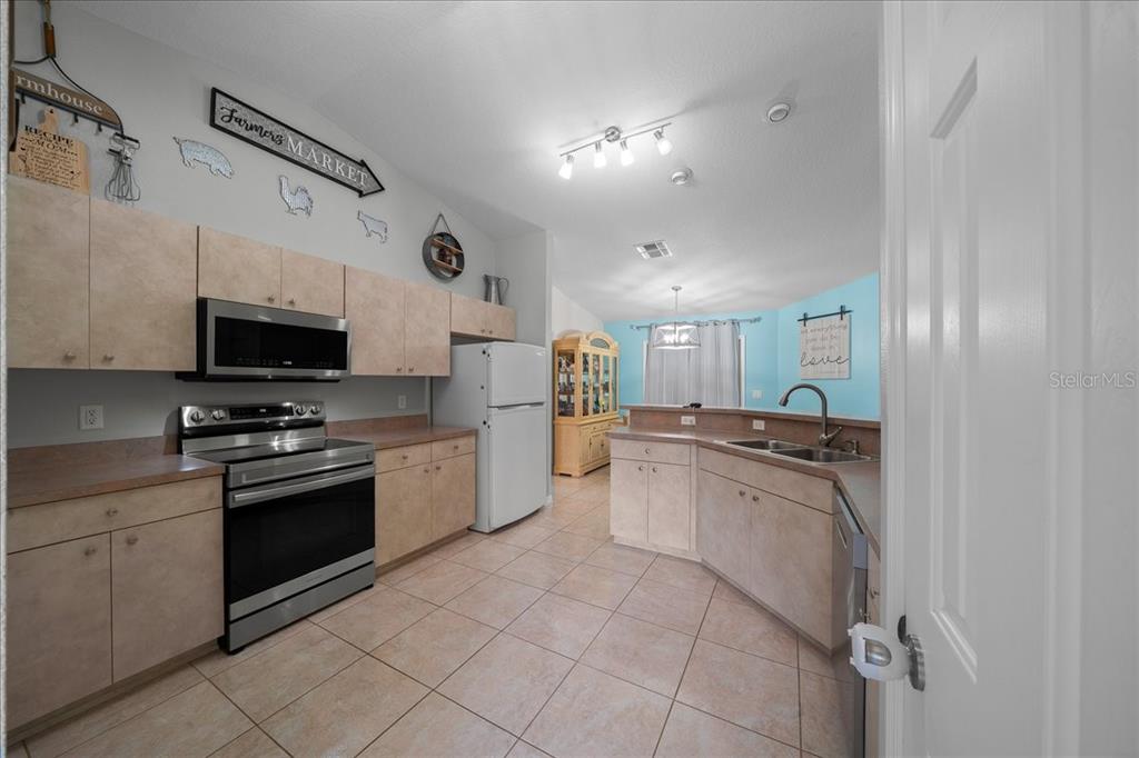5321 Southwest 115th Loop Ocala, FL 34476 - Photo 24 of 49 a kitchen with stainless steel appliances granite countertop a sink and dishwasher a refrigerator with white cabinets