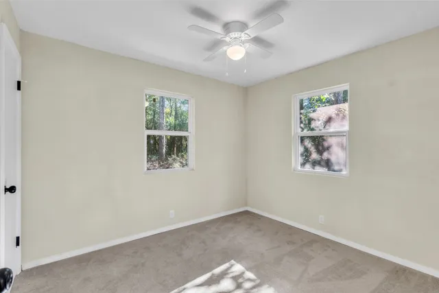 an empty room with windows and fan