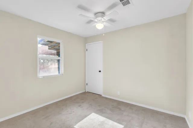 an empty room with a window and a ceiling fan