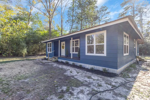 a view of a house with a yard and large tree