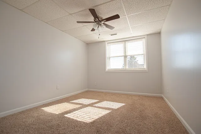 an empty room with a window and a ceiling fan