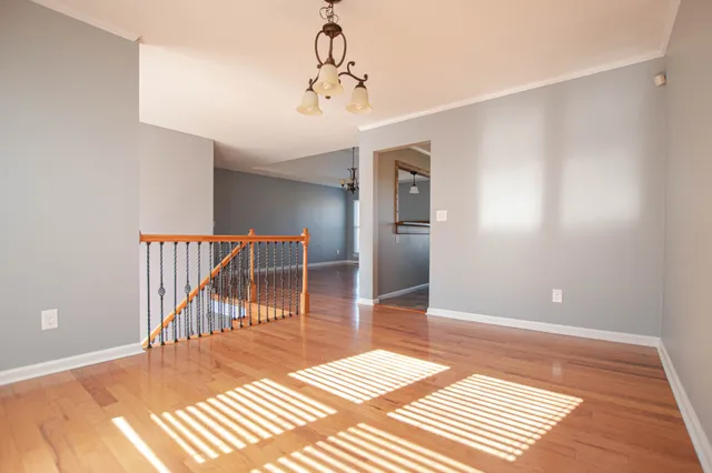 a view of a hallway with wooden floor and a chandelier