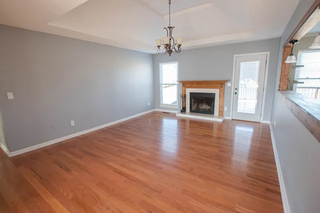 an empty room with wooden floor fireplace and windows