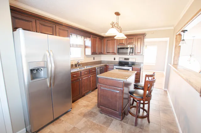 a kitchen with stainless steel appliances granite countertop a refrigerator a sink a stove a table and chairs